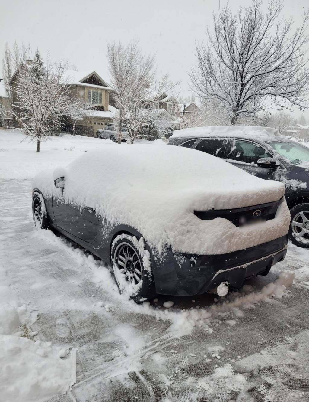 Car parked in a driveway covered in fresh snow
